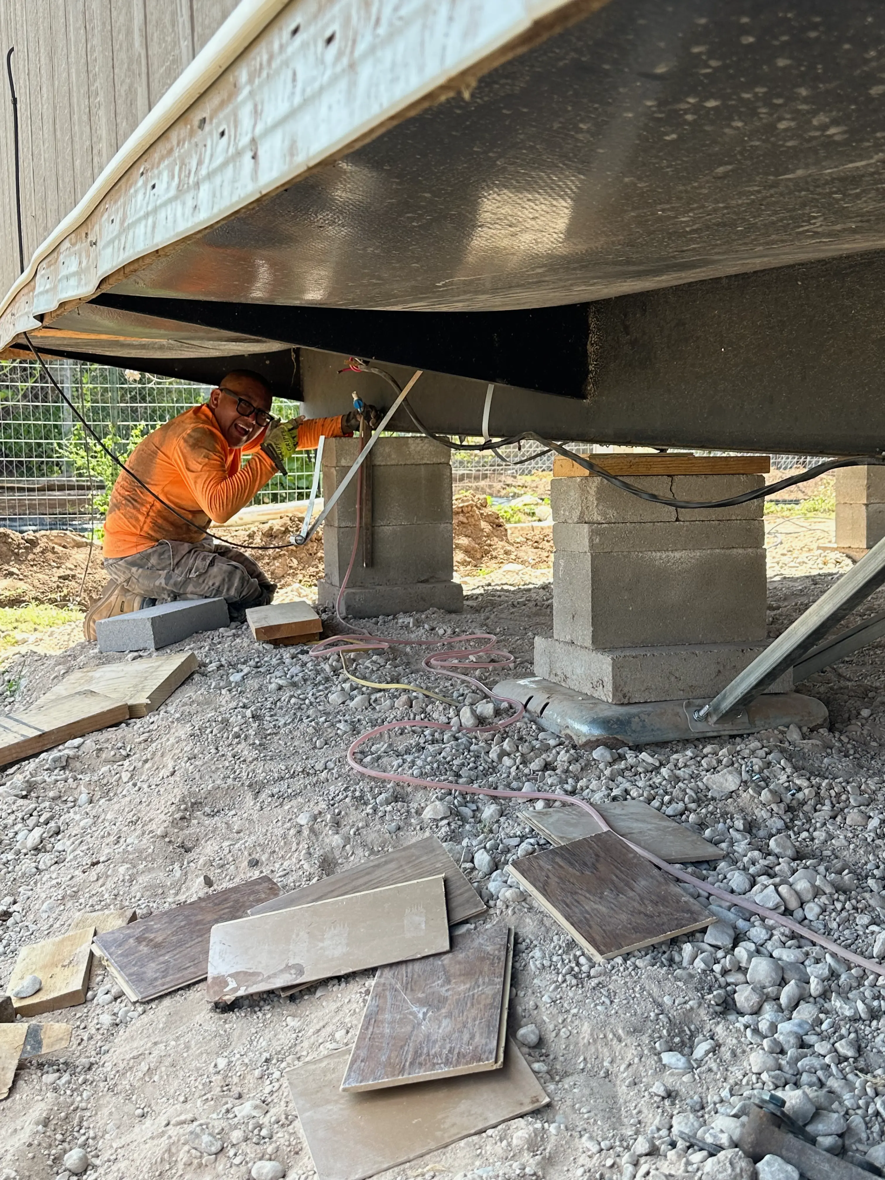 A man working underneath a mobile home.