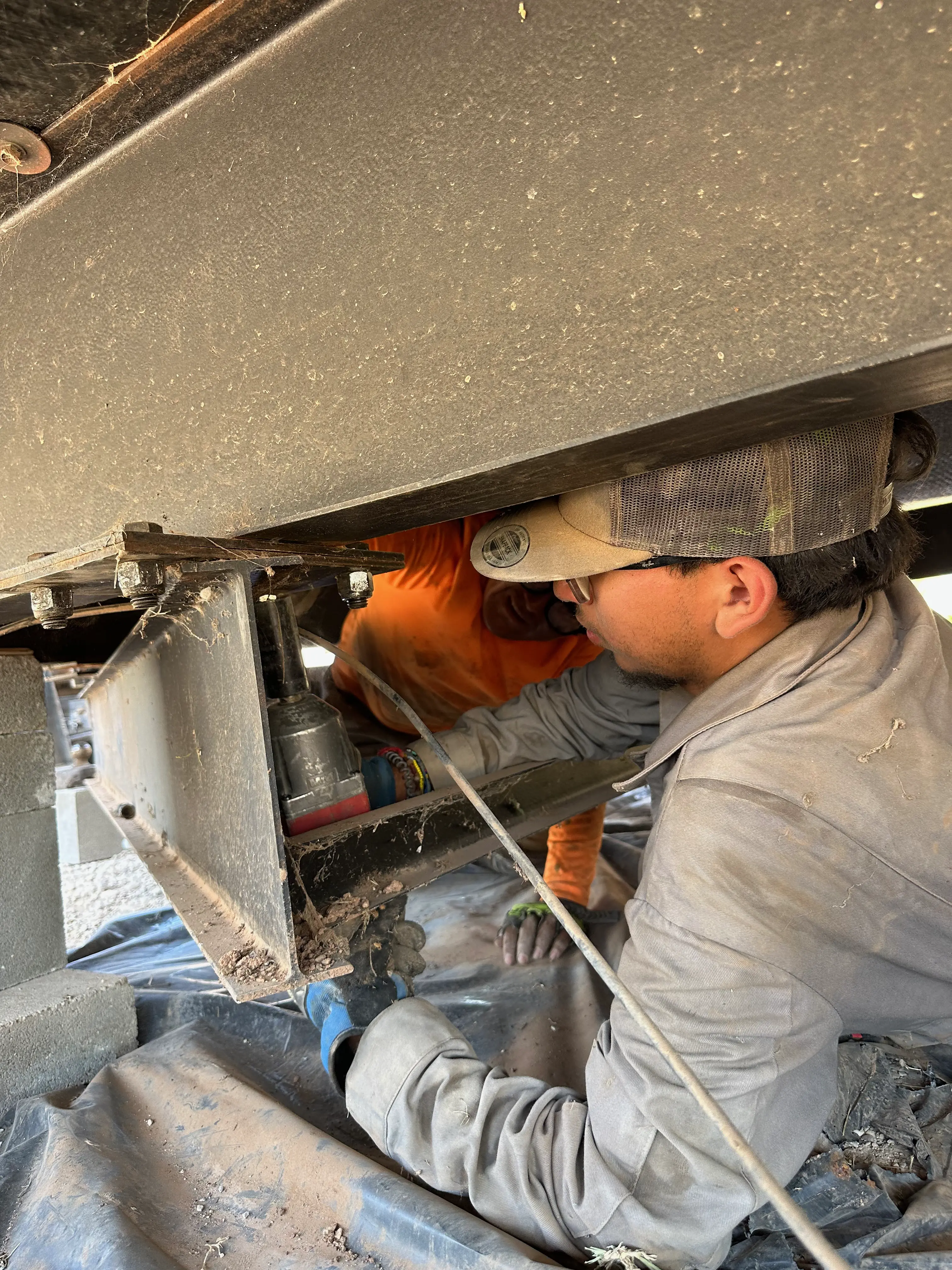 A man working underneath a mobile home -- using a power tool.